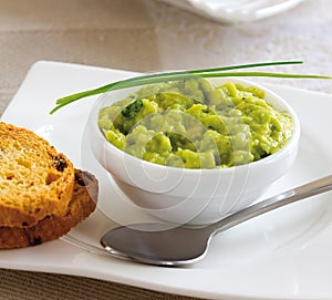 Mexican guacamole served in a bowl with toast. photo